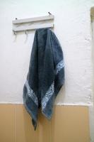 dark blue wet towel hung on the bathroom wall photo