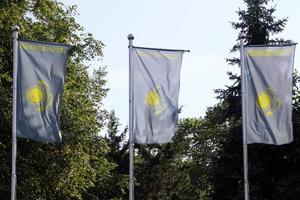 tres banderas nacionales de kazajstán en postes de bandera en la ciudad de almaty en un día soleado foto