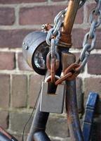 Close-up of a rusty, but sturdy padlock with a metal chain attached to it photo