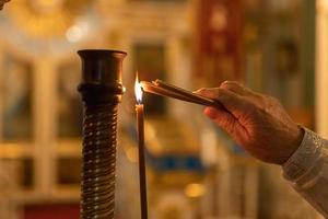 Orthodox Church. Christianity. Hand of priest lighting burning candles in traditional Orthodox Church on Easter Eve or Christmas. Religion faith pray symbol.