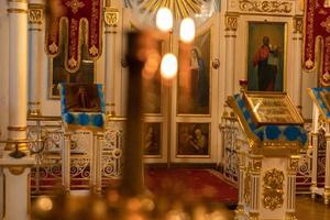 Iglesia Ortodoxa. cristiandad. decoración interior festiva con velas encendidas e icono en la iglesia ortodoxa tradicional en vísperas de pascua o navidad. religión fe orar símbolo. foto