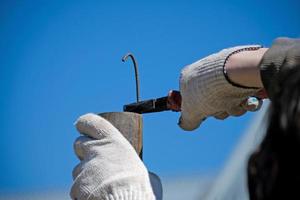 The technician keeps bending the metal rod in his hand with pliers. Pliers in the hands of men. Electrician. photo
