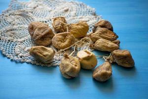 Bunch dried figs on on a knitted napkin on a blue table. Dried fruit. photo