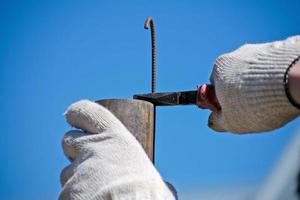 The technician keeps bending the metal rod in his hand with pliers. Pliers in the hands of men. Electrician. photo