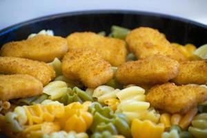 pasta con nuggets de pollo en una sartén. nuggets de pollo frito. sabrosos y crujientes nuggets de pollo. Menu de niños. foto