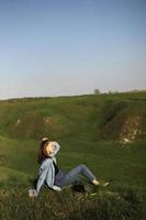 Young woman is sitting on green grass hills and feeling relax on summer sunny day photo