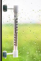 window glass with rain drops and thermometer photo