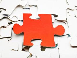 one red piece on pile of white jigsaw puzzles photo