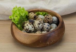 Quail eggs in a bowl on wooden background photo