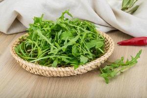 Ruccola in a basket on wooden background photo