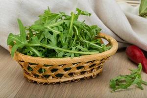 ruccola en una cesta sobre fondo de madera foto