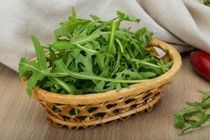 Ruccola in a basket on wooden background photo