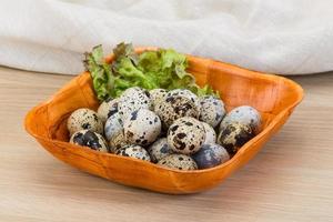 Quail eggs in a bowl on wooden background photo
