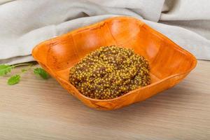 French mustard in a bowl on wooden background photo