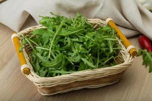 Ruccola in a basket on wooden background photo