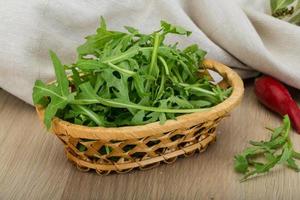 ruccola en una cesta sobre fondo de madera foto