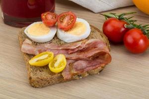 Sándwich de tocino sobre fondo de madera foto