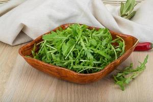 Ruccola in a bowl on wooden background photo