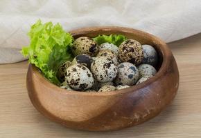 Quail eggs in a bowl on wooden background photo