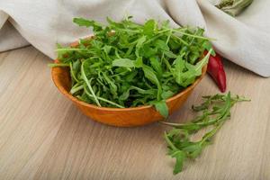 Ruccola in a bowl on wooden background photo