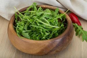 Ruccola in a bowl on wooden background photo