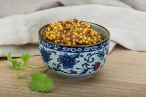 French mustard in a bowl on wooden background photo