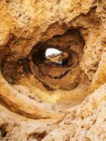 hole in eroded sandstone mount on beach photo