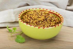 French mustard in a bowl on wooden background photo