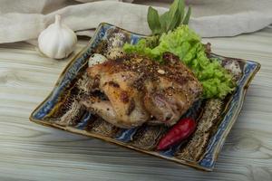 codorniz a la parrilla en el plato y fondo de madera foto