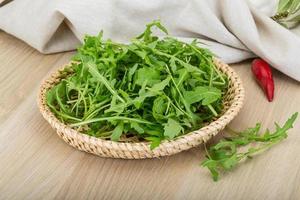 Ruccola in a basket on wooden background photo