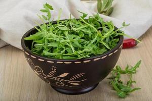 Ruccola in a bowl on wooden background photo