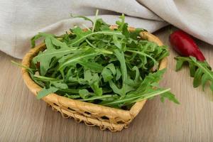 Ruccola in a bowl on wooden background photo