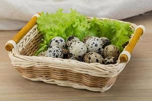 Quail eggs in a basket on wooden background photo