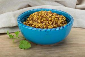 French mustard in a bowl on wooden background photo