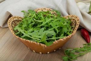 Ruccola in a basket on wooden background photo