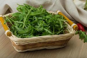 ruccola en una cesta sobre fondo de madera foto