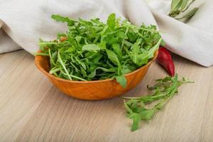 Ruccola in a bowl on wooden background photo