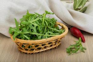 ruccola en una cesta sobre fondo de madera foto