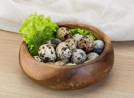 Quail eggs in a bowl on wooden background photo