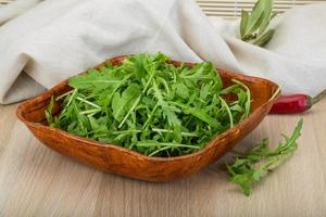 Ruccola in a bowl on wooden background photo