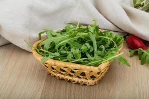 ruccola en una cesta sobre fondo de madera foto