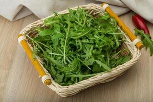 Ruccola in a basket on wooden background photo