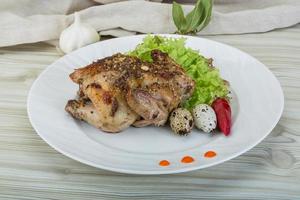 Quail grilled on the plate and wooden background photo