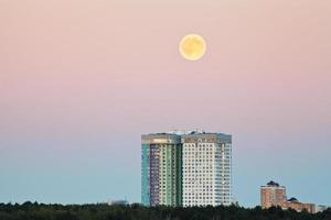 luna llena en cielo rosa sobre casas urbanas foto