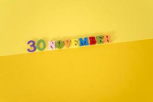 September 30 on a yellow and paper background with wooden and multicolored letters with space for text. photo