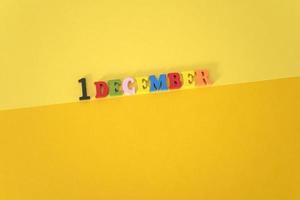 December 1 on a yellow and paper background with wooden and multicolored letters with space for text. photo