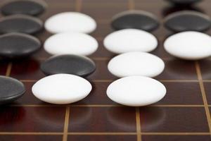 stones during go game playing on wooden desk photo