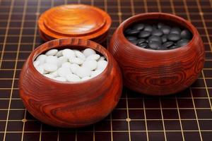 black and white go stones in wooden bowls photo