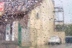 rain trickles on windscreen and blurred house photo