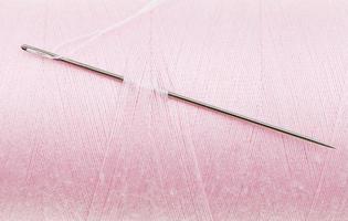 aguja de coser a mano en bobina de hilo rosa foto